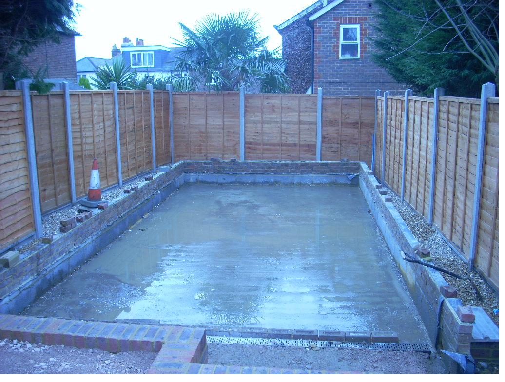 Finished concrete base poured within brick retaining walls on a residential groundworks project