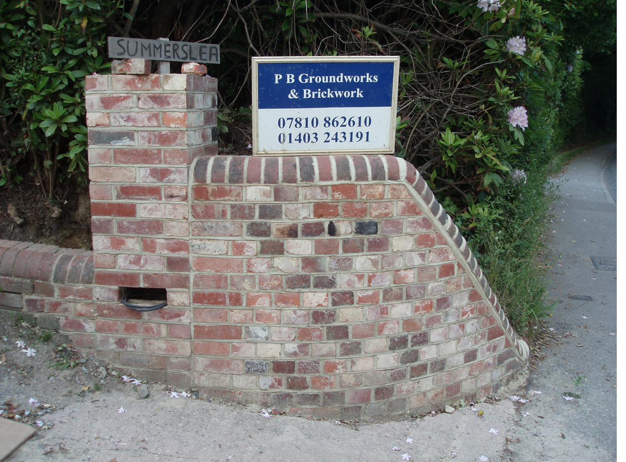 Finished curved brick wall with PB Groundworks signage in Lingfield, Surrey