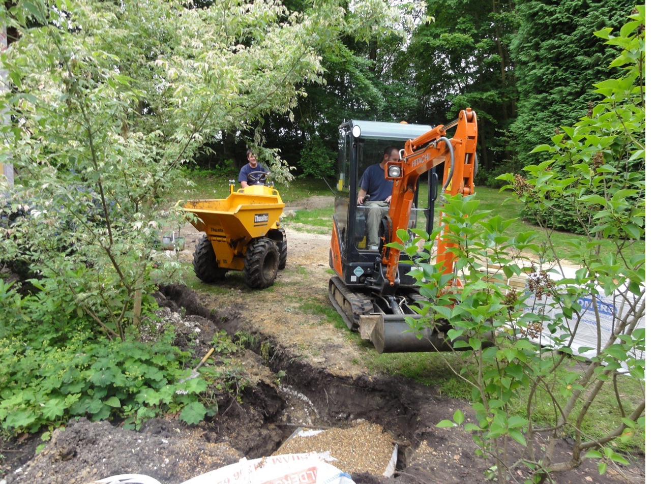 Drainage trench excavation with mini digger and dumper on a residential site
